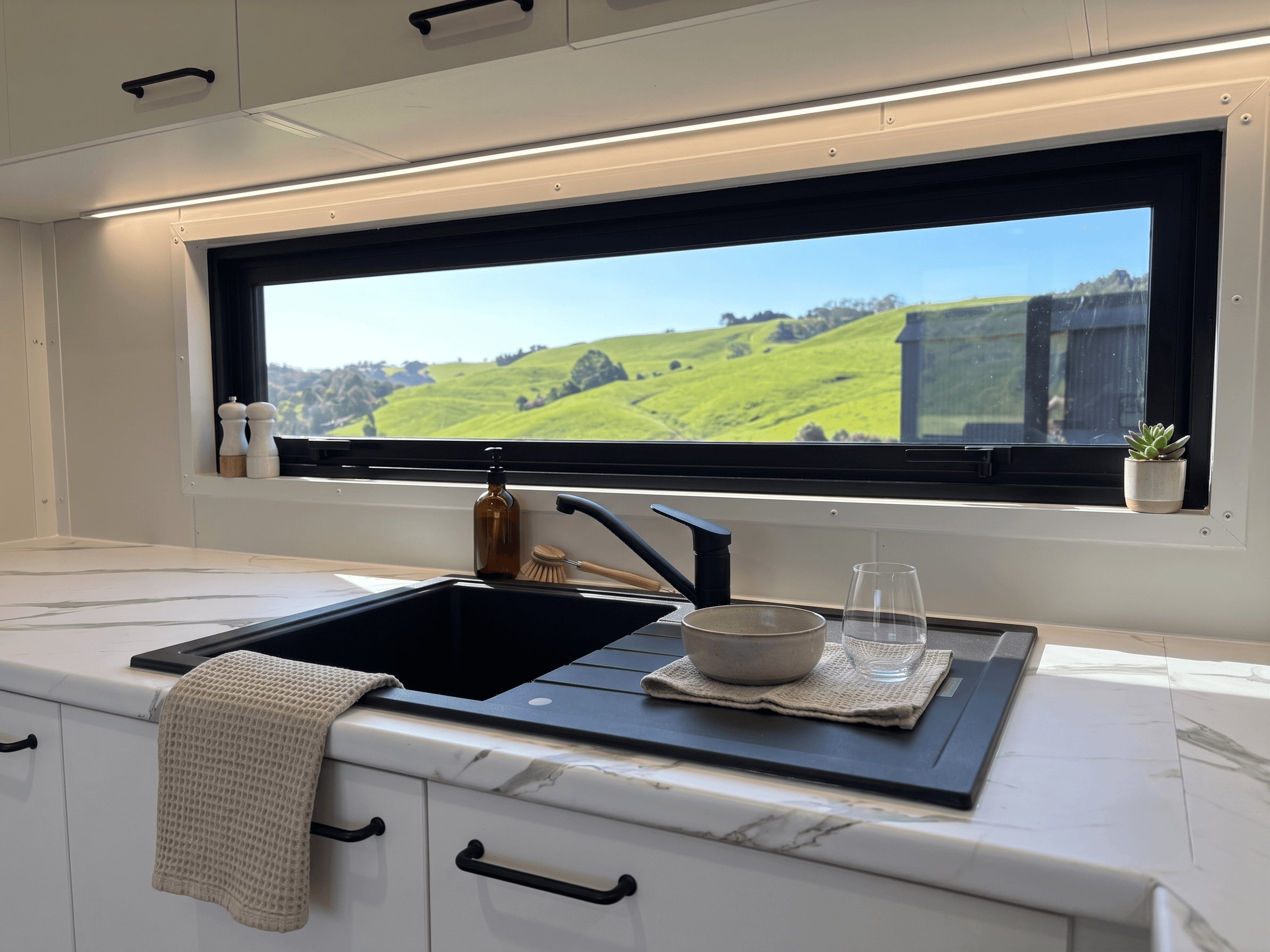 Kitchen with black granite sink and picture window overlooking rolling New Zealand hills