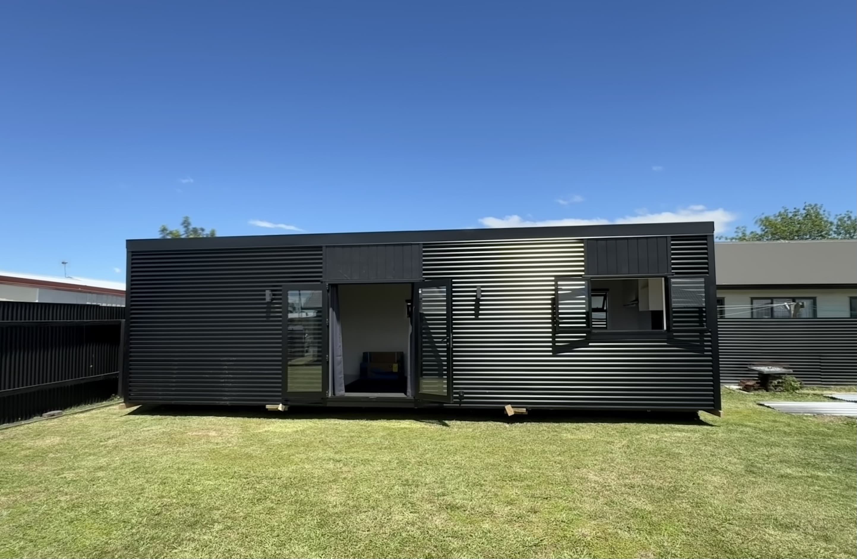 10×3.5 black NZ-made tiny home on a grassed residential site