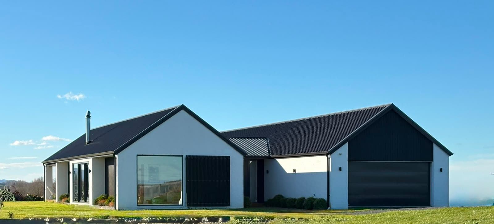 Transportable family home with pitched gable roof, white Coloursteel® cladding and dark metal roof on a rural section